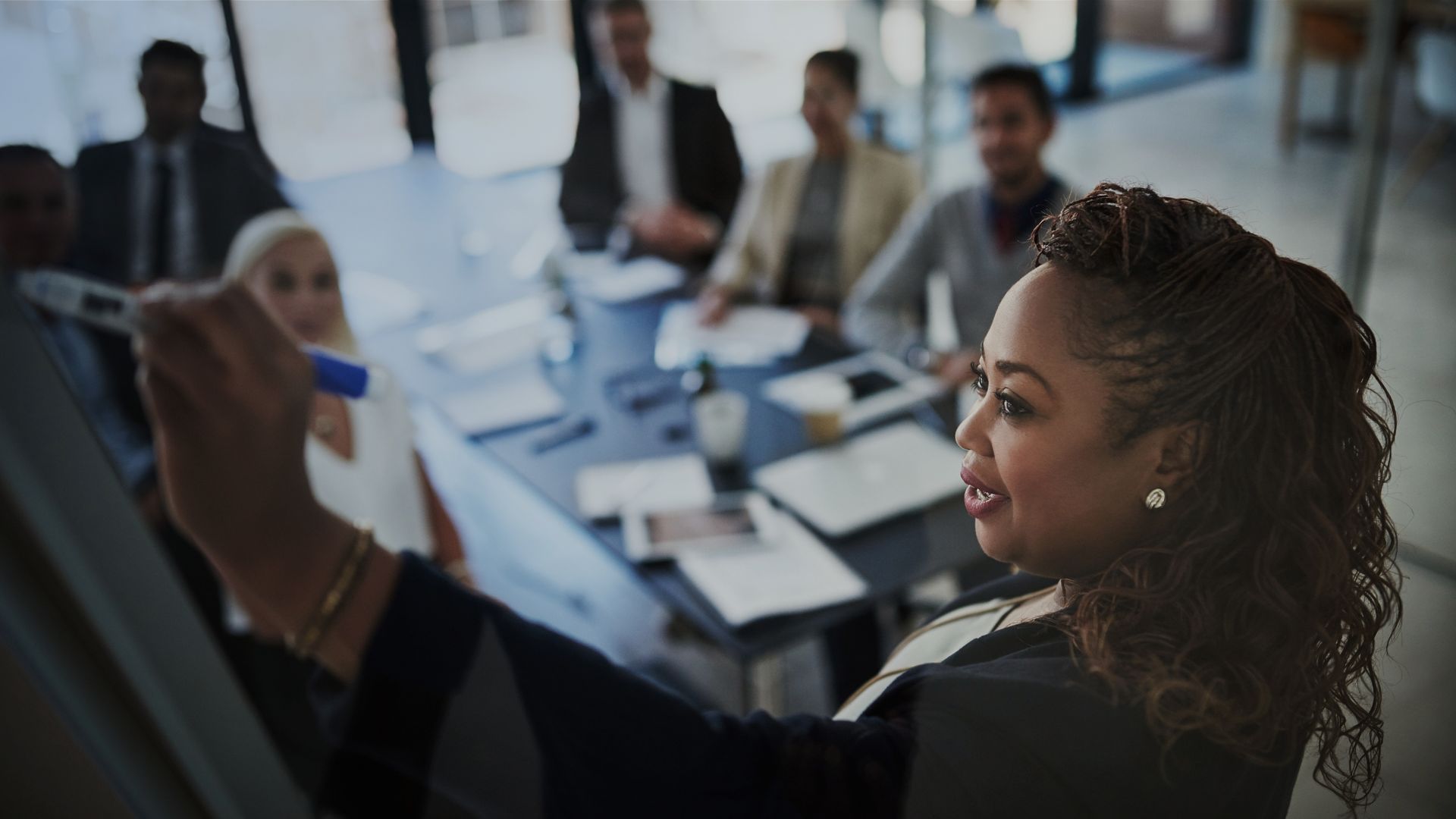 Woman writing on a whiteboard during a meeting